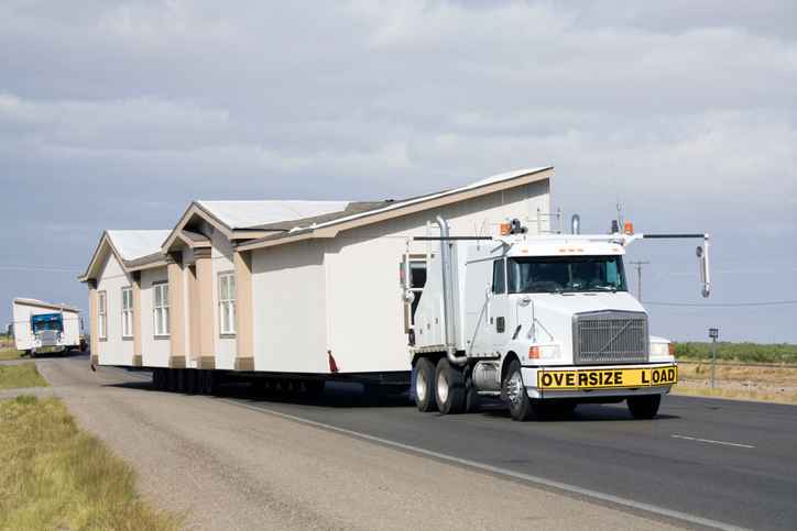 Semis moving two manufactured homes to new lots