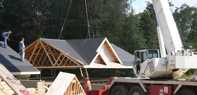 Construction crew placing manufactured home roof on new property